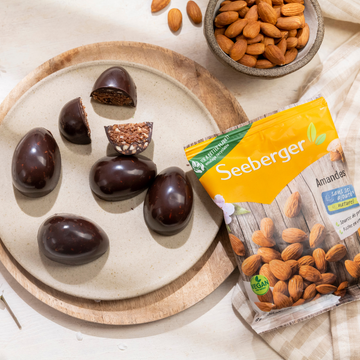 Œufs crus au chocolat et au brownie aux amandes sur une table en bois avec du cacao, des dattes et des amandes en arrière-plan.