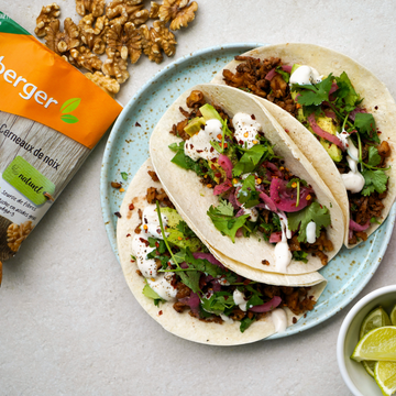 Zwei Tacos liegen auf einem Teller, gefüllt mit Salat, Avocado und Soße.